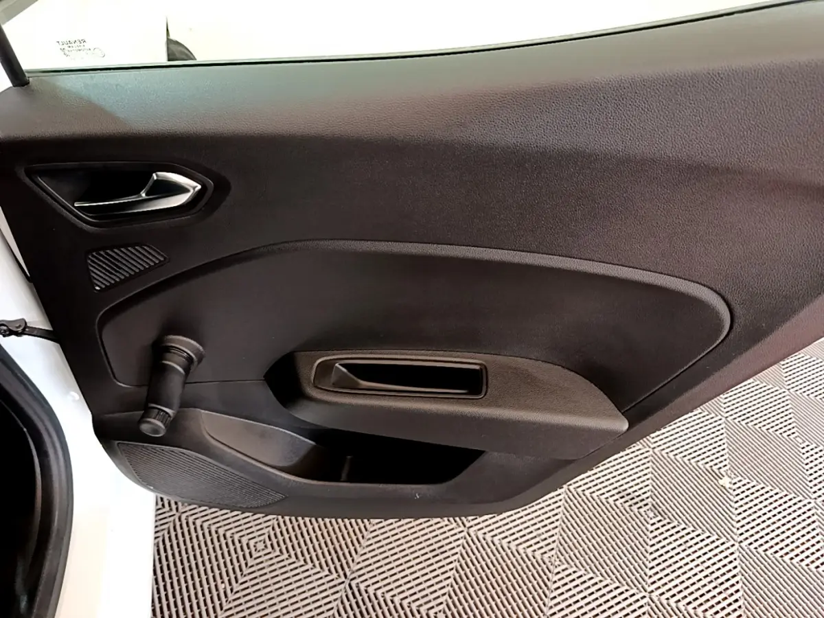 Vue intérieure côté gauche de la porte avant blanche d'une Renault Clio Business avec poignée manuelle de vitre.