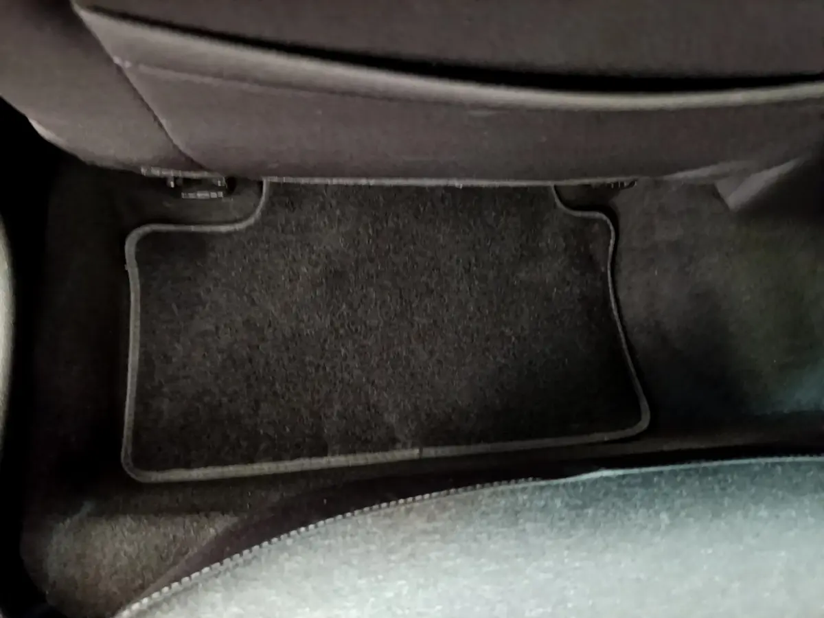 Vue rapprochée du tapis de sol noir côté passager arrière d’une Renault Clio Business Blue dCi 85 blanche de 2020.