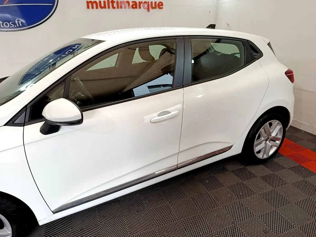 Profil côté gauche d'une Renault Clio Business Blue dCi 85 blanche, avec jantes alliage et logo Clio sur la bas de porte.