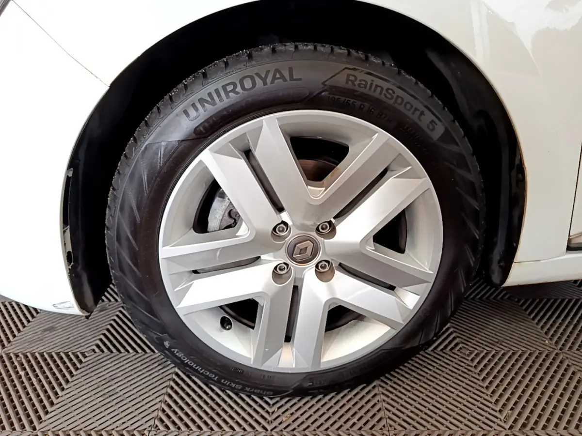 Gros plan sur la roue avant droite blanche d'une Renault Clio Business Blue dCi 85 avec jante alliage argentée.