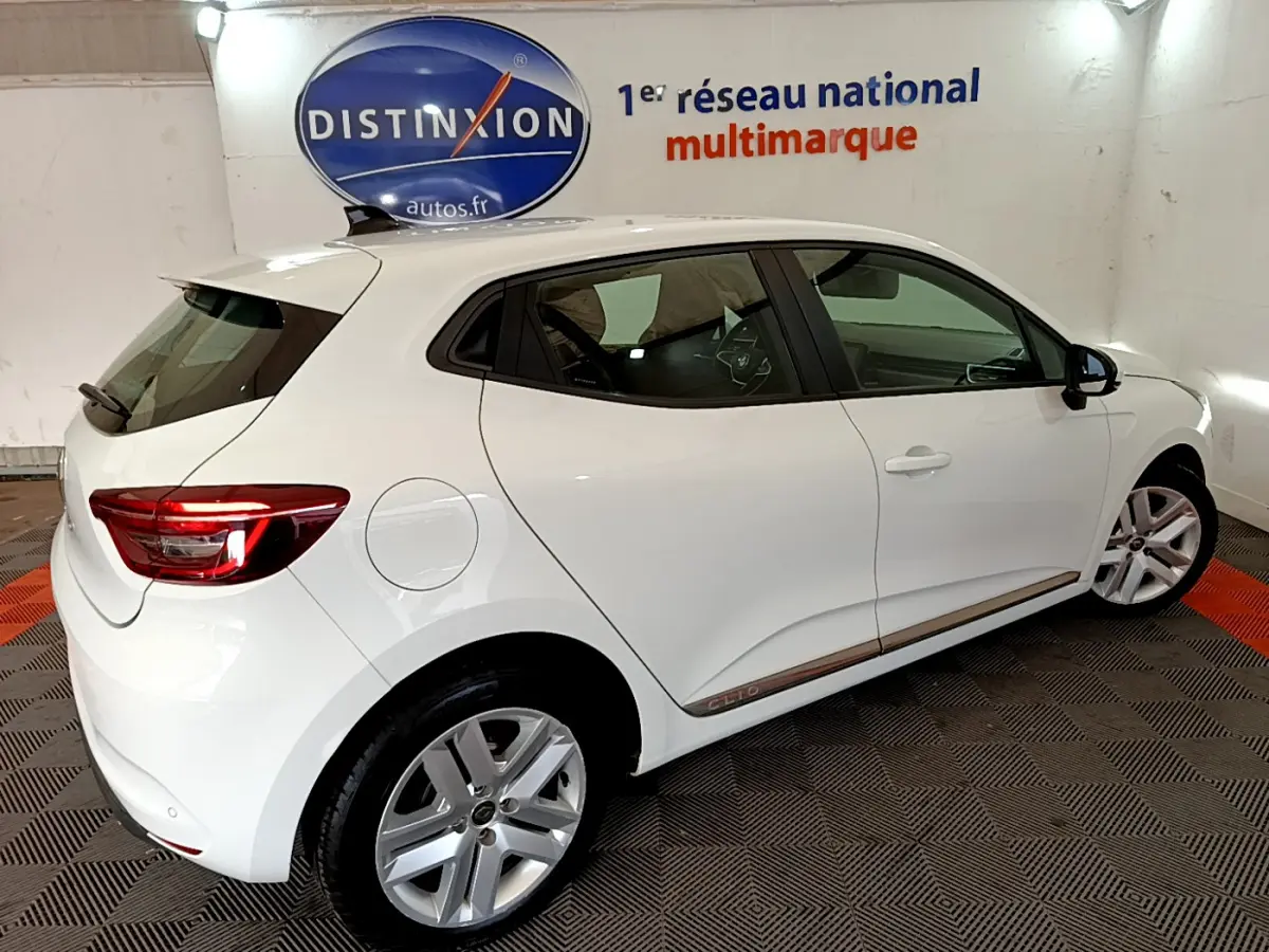 Renault Clio Business Blue dCi 85 blanc vue de profil côté droit en intérieur avec logo Distinxion en arrière-plan.