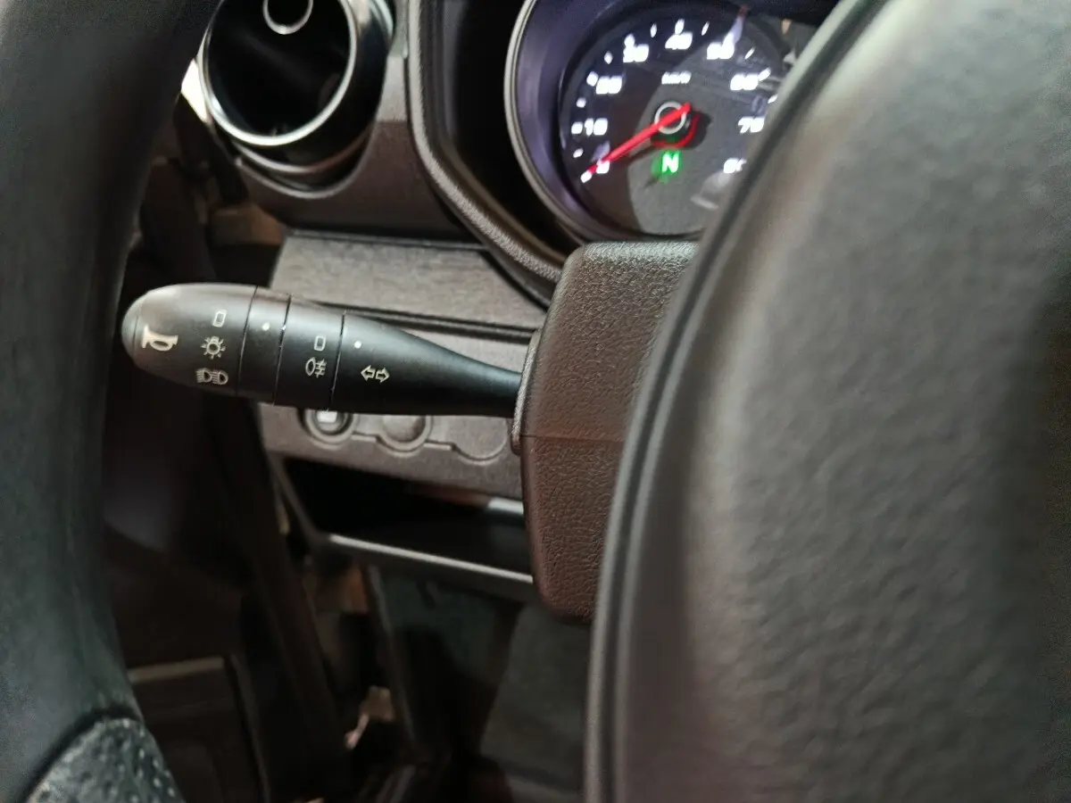 Gros plan sur le commodo d’éclairage à gauche du volant dans l’habitacle de l’AIXAM Ambition gris clair 2026.