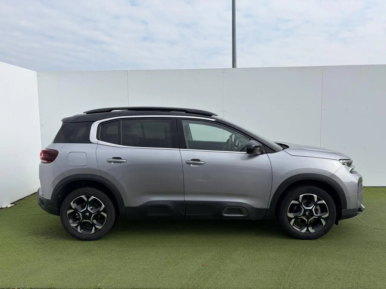 Profil droit du Citroën C5 Aircross gris métal 2024 avec toit noir et jantes alliage bi-ton distinctives.