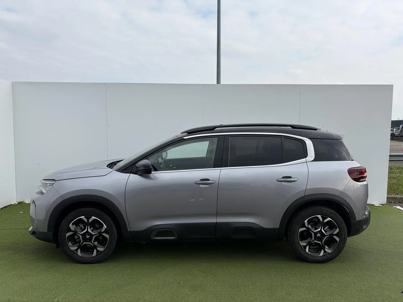 Profil droit d'un Citroën C5 Aircross gris métal 2024 avec toit noir bi-ton et jantes alliage 18 pouces.