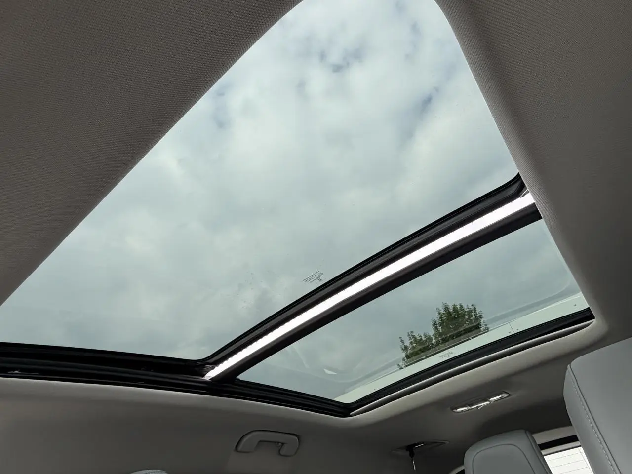 Vue intérieure du toit ouvrant panoramique vitré du Citroën C5 Aircross gris métal, avec ciel nuageux visible.