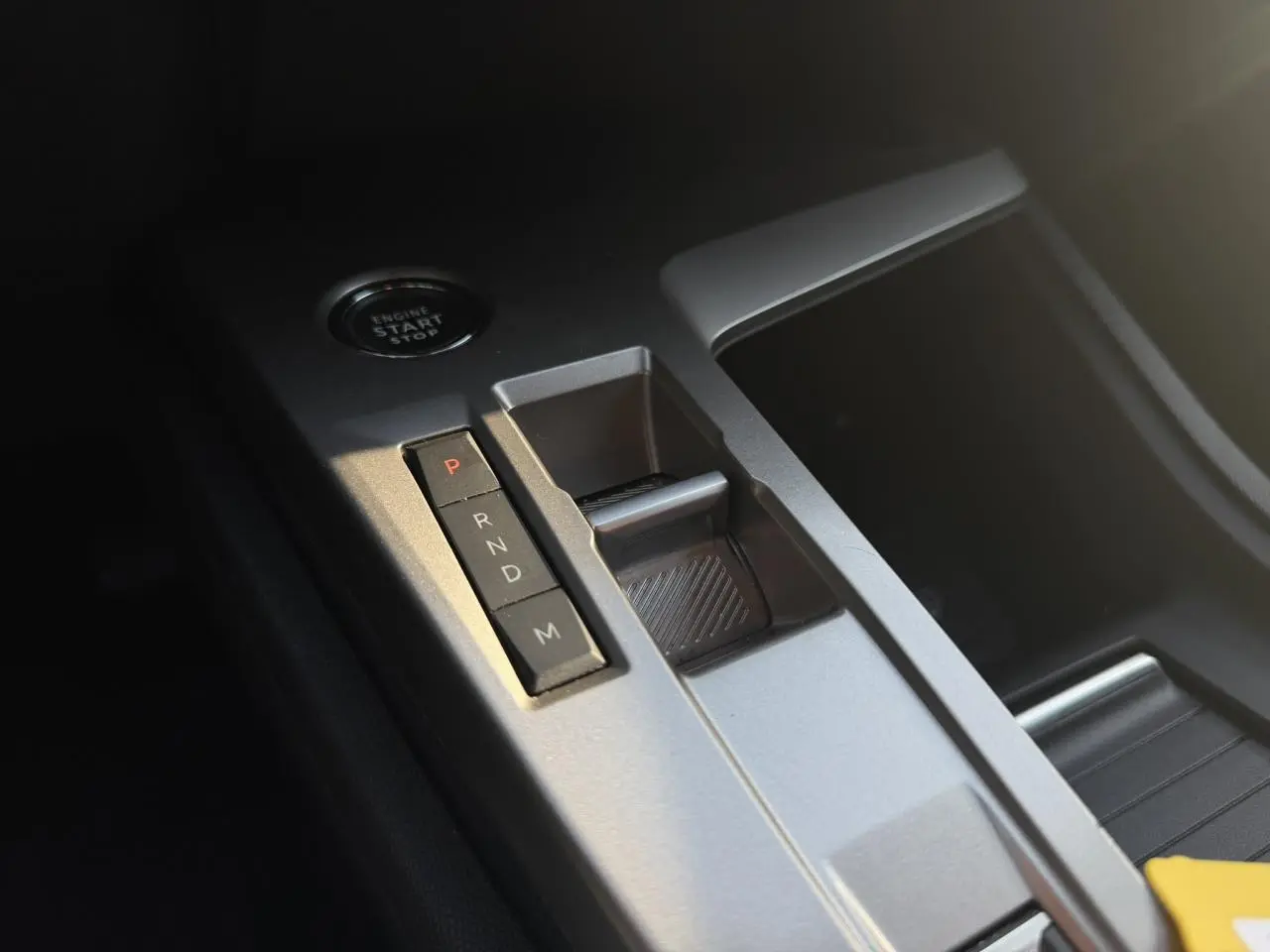 Gros plan sur la console centrale grise avec sélecteur de boîte automatique et bouton start/stop dans une Peugeot 308 noire.