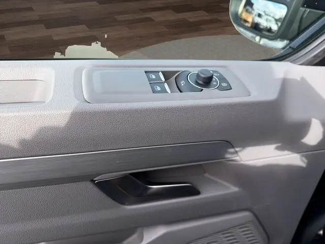 Détail de la porte côté conducteur du Volkswagen Transporter noir 2026, avec commandes des vitres et rétroviseur électrique.