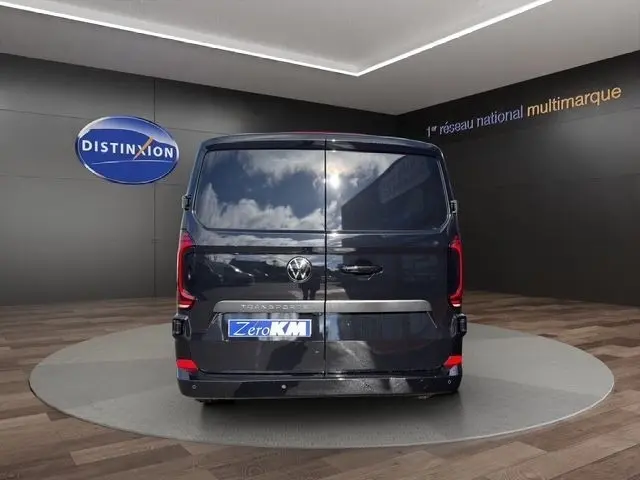 Vue arrière d'un Volkswagen Transporter noir 2026, portes battantes fermées, dans un showroom avec logo Distinxion.