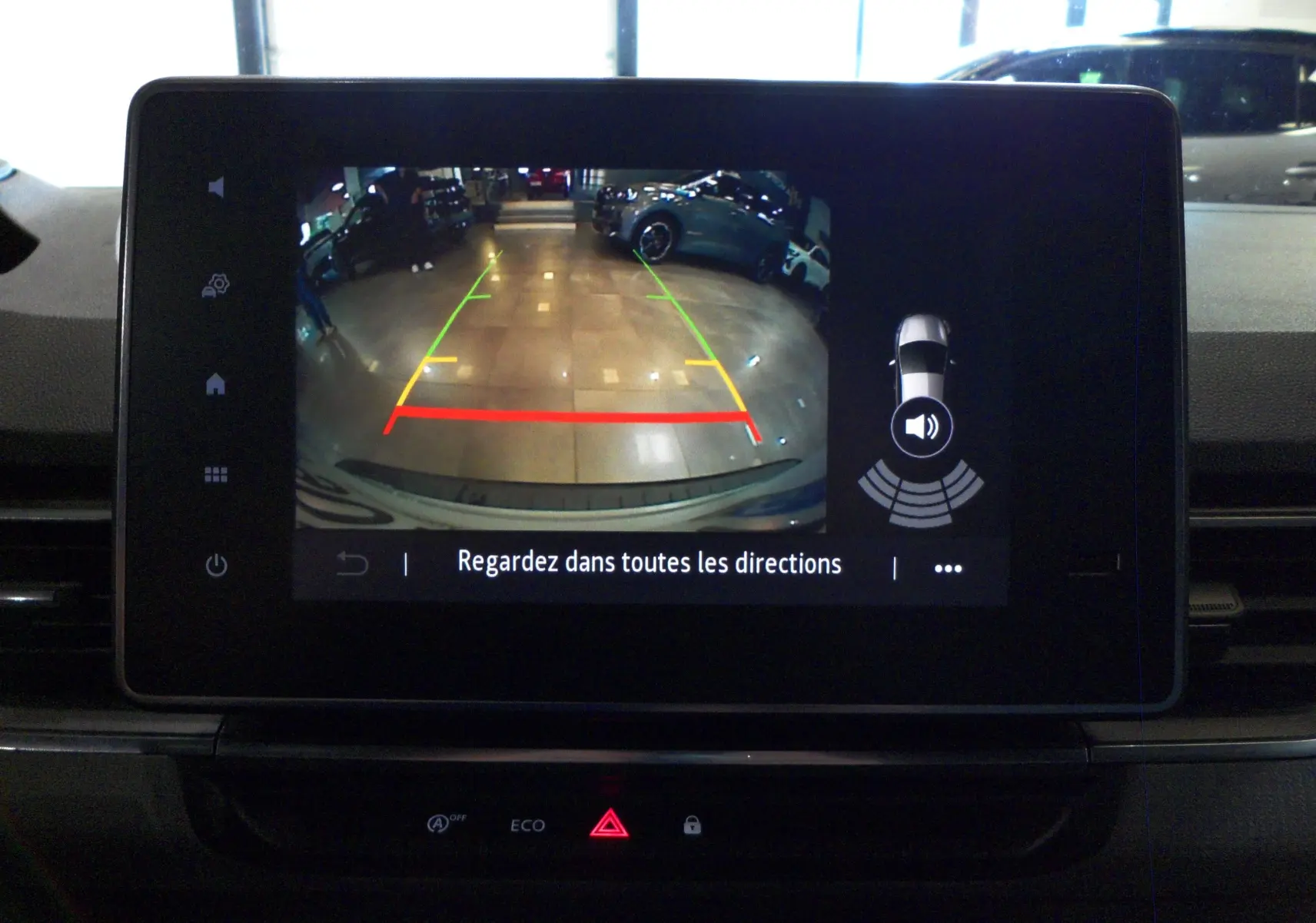 Écran central montrant la caméra de recul active du Renault Kangoo Van blanc minéral, avec repères colorés et alertes de proximité.