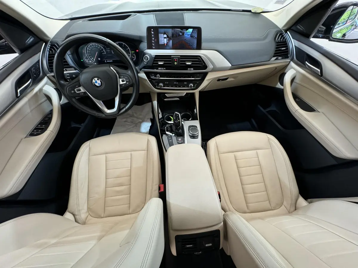 Intérieur beige clair de BMW X3 xDrive30d 2018 vu de dessus, avec tableau de bord moderne et écran tactile central.