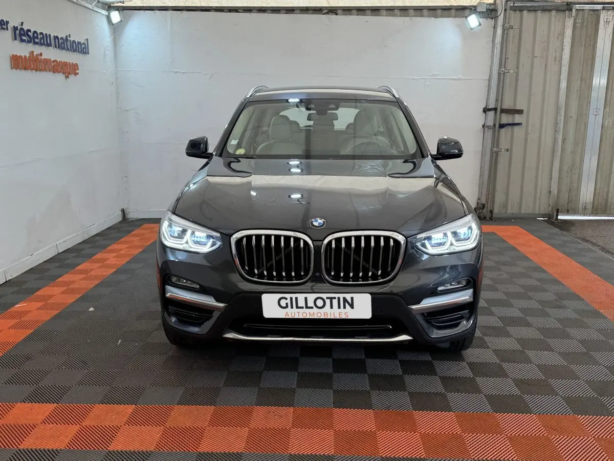 Vue frontale d'un BMW X3 gris foncé avec phares LED allumés et calandre double haricot caractéristique.