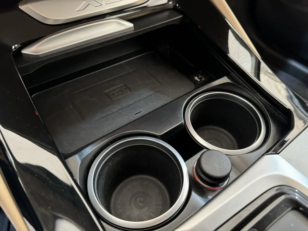Gros plan sur la console centrale noire du BMW X3 2018 avec porte-gobelets et zone de recharge sans fil.