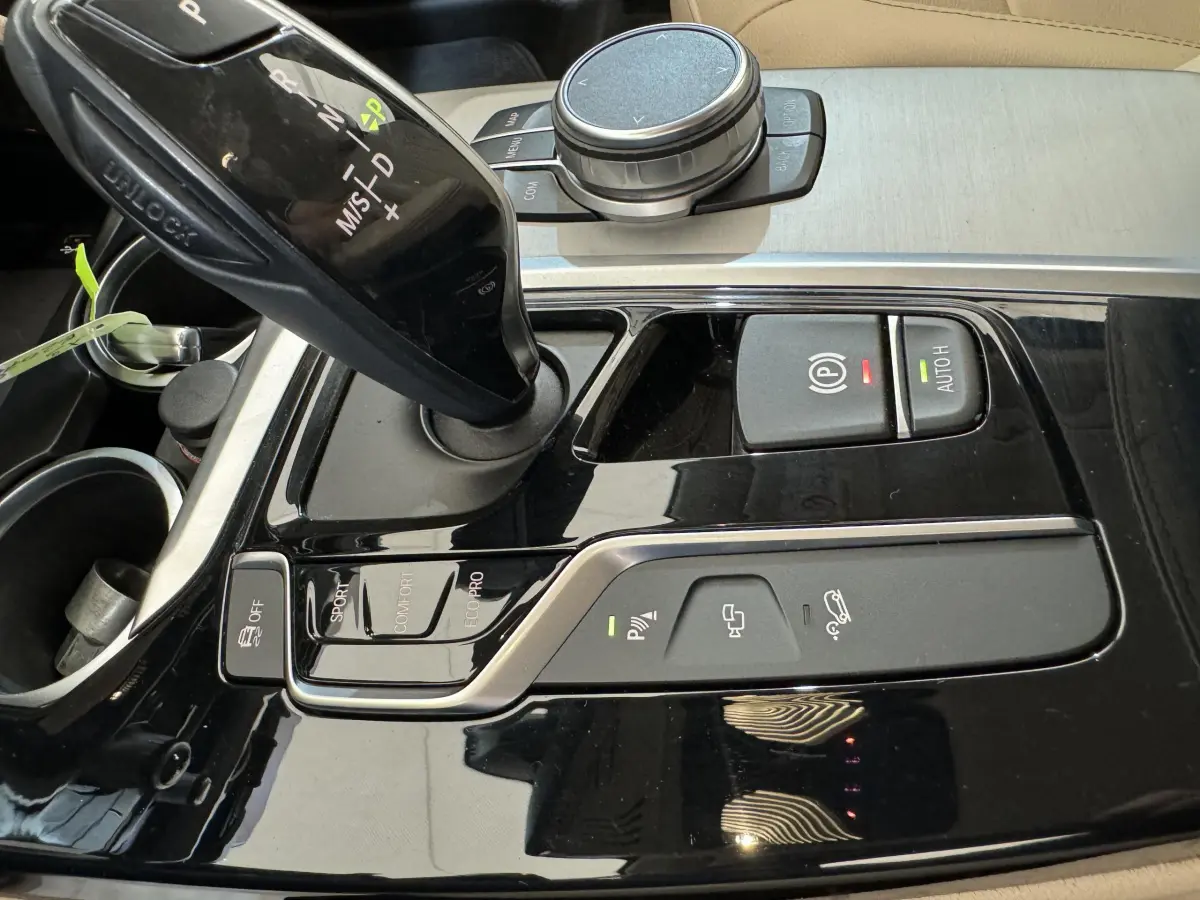 Gros plan sur la console centrale noire brillante du BMW X3 xDrive30d, montrant levier de vitesses et commandes de conduite.