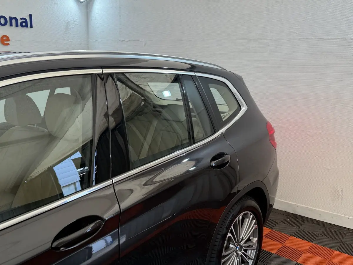 Vue latérale arrière droite d'un BMW X3 gris foncé avec jantes alliage et vitres teintées dans un garage.