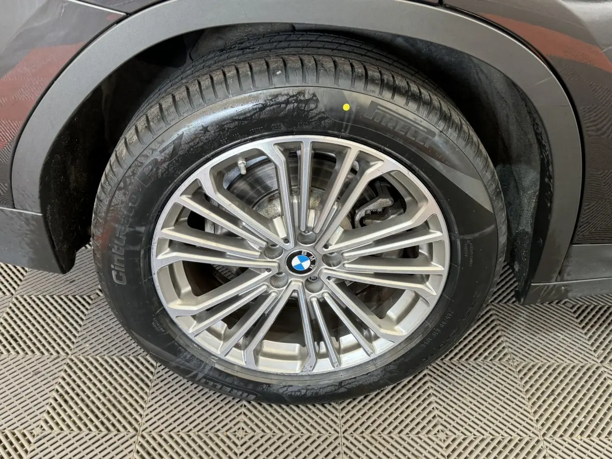 Gros plan sur la roue avant droite d'un BMW X3 gris foncé, mettant en valeur la jante alliage multi-branches et le pneu.