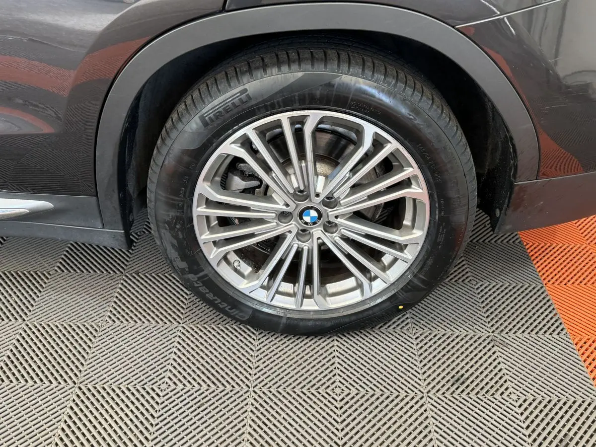Gros plan sur la roue arrière droite d’un BMW X3 gris foncé avec jante alliage multi-branches et pneu Pirelli.