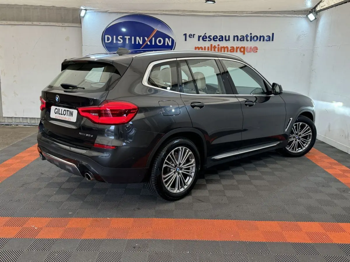 BMW X3 xDrive30d gris foncé vu en 3/4 arrière droit dans un showroom avec jantes alliage et feux LED.