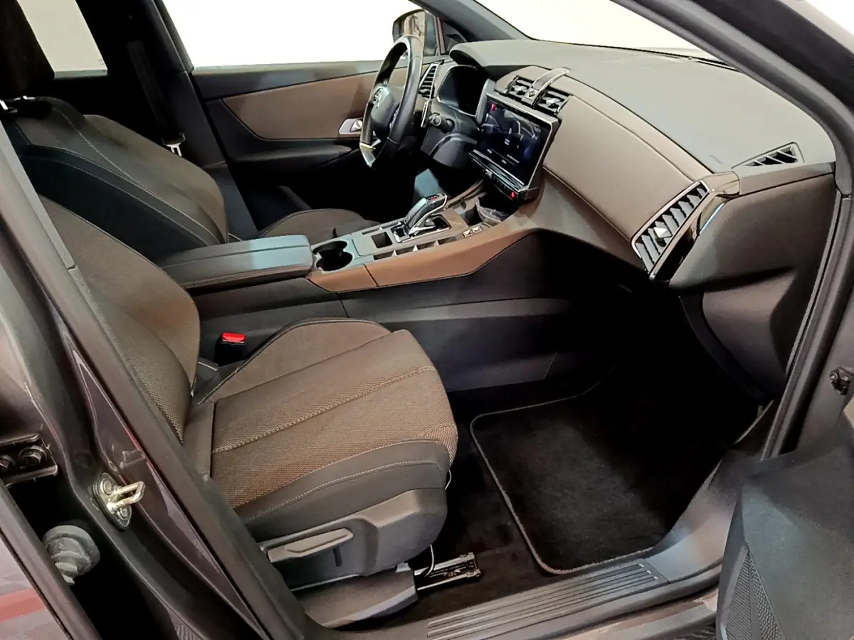Intérieur avant droit du DS7 Crossback gris foncé, avec tableau de bord moderne et sièges tissu noirs.