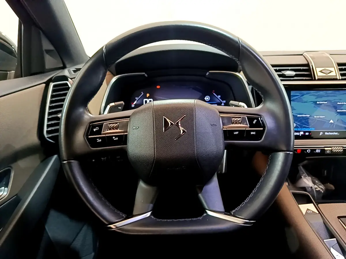 Vue intérieure centrée sur le volant cuir noir du DS7 Crossback 2020, avec tableau de bord numérique et écran tactile visible.