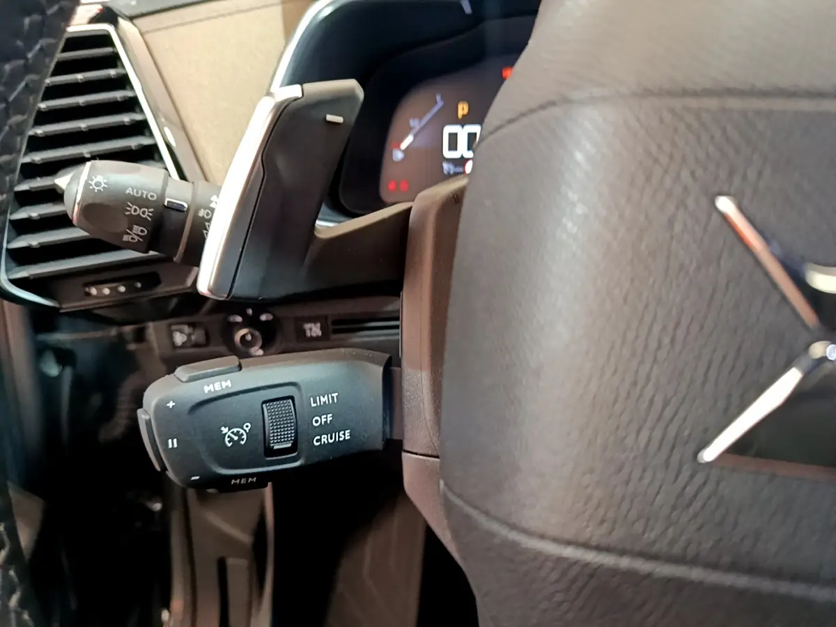 Gros plan sur la commande de régulateur de vitesse à gauche du volant cuir gris foncé du DS7 Crossback 2020.