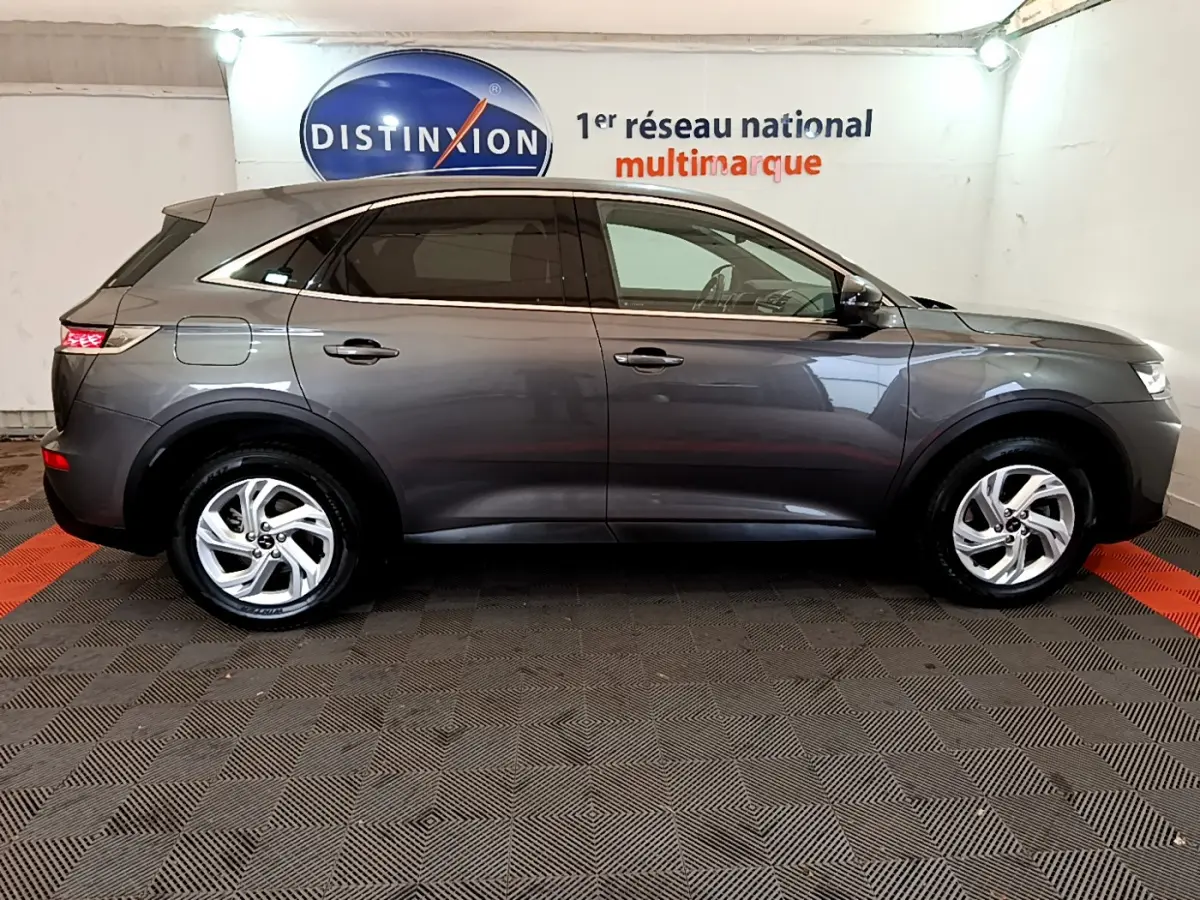 Vue profil droit d'un DS7 Crossback gris foncé 2020 garé en intérieur, soulignant ses lignes élégantes et ses jantes alliage.