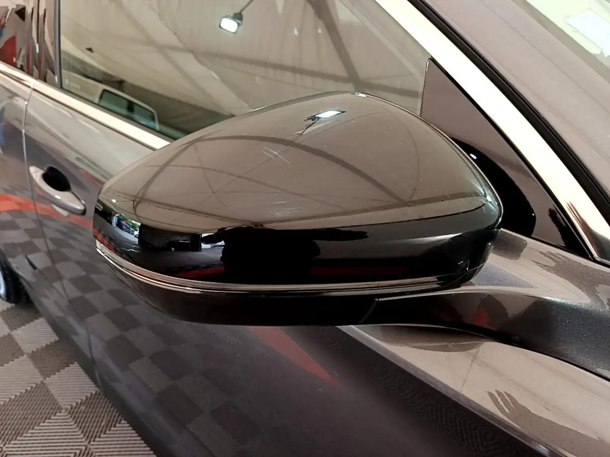 Rétroviseur noir brillant côté conducteur d'un DS7 Crossback gris foncé, vue rapprochée sur la portière avant.