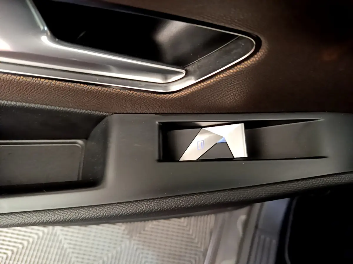 Gros plan sur le bouton de verrouillage centralisé côté gauche, intérieur noir du DS7 Crossback gris foncé.