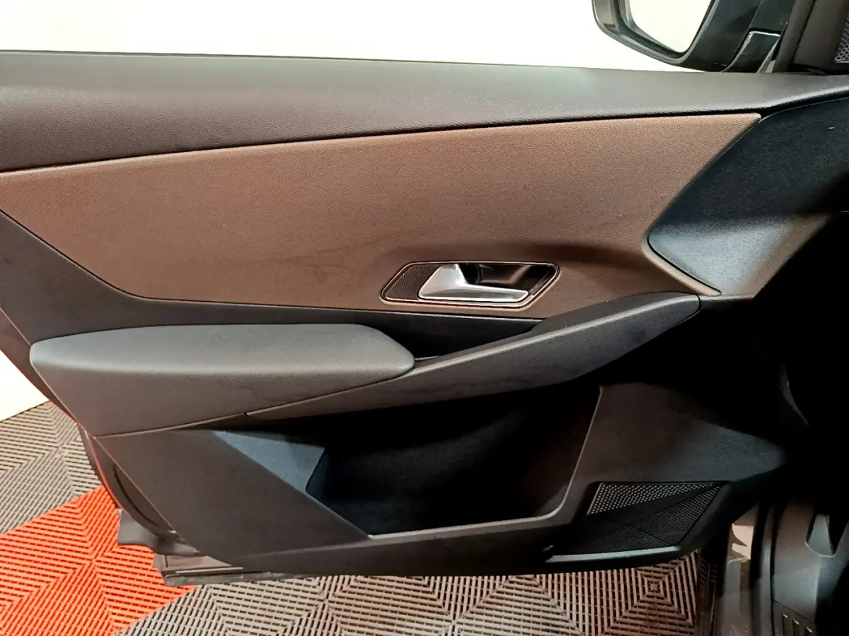 Vue rapprochée de la porte côté droit intérieure du DS7 Crossback gris foncé, avec poignée argentée et panneau bicolore.