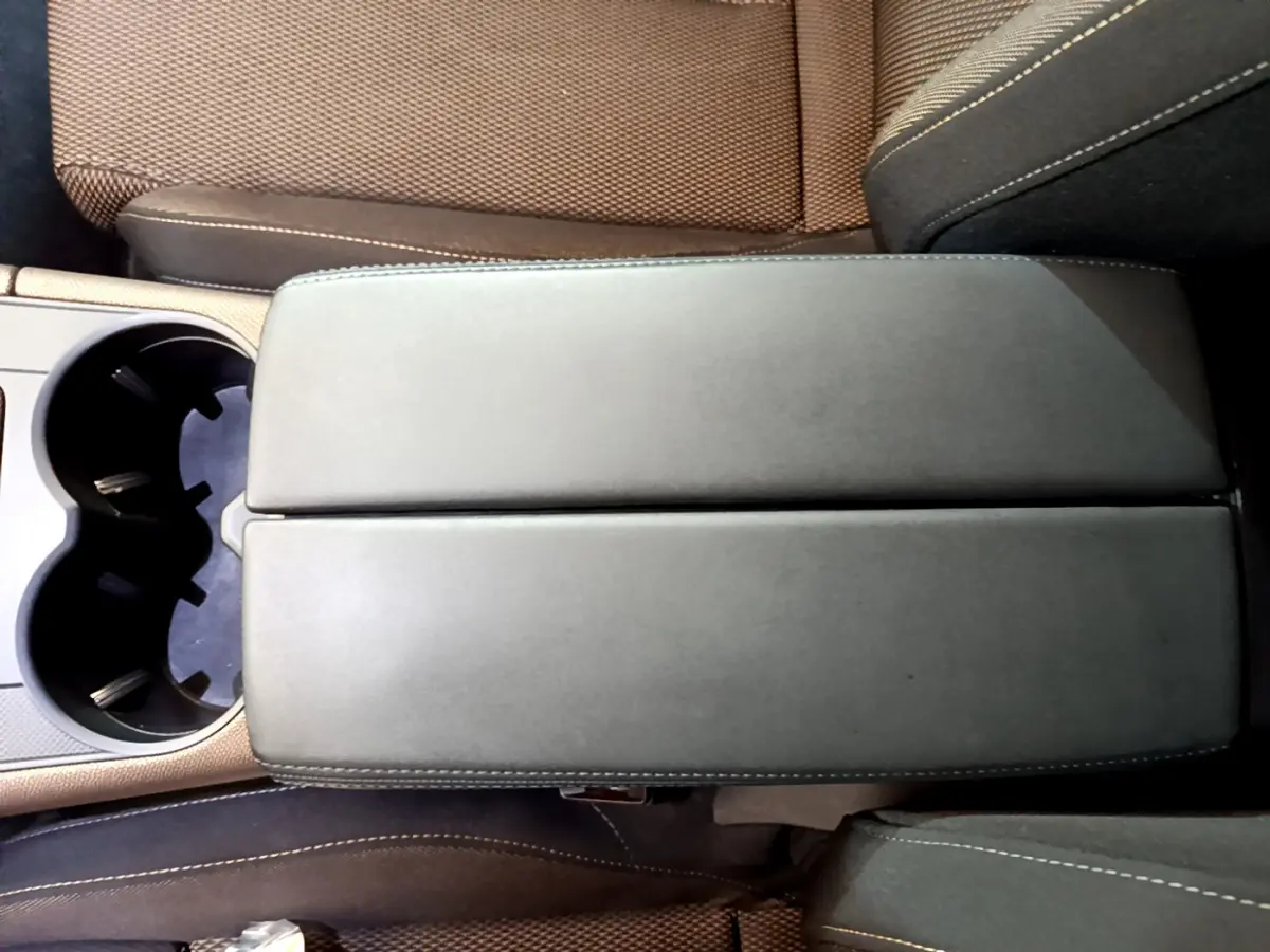 Vue plongeante sur l'accoudoir central en cuir noir et les sièges marron du DS7 Crossback 2020.