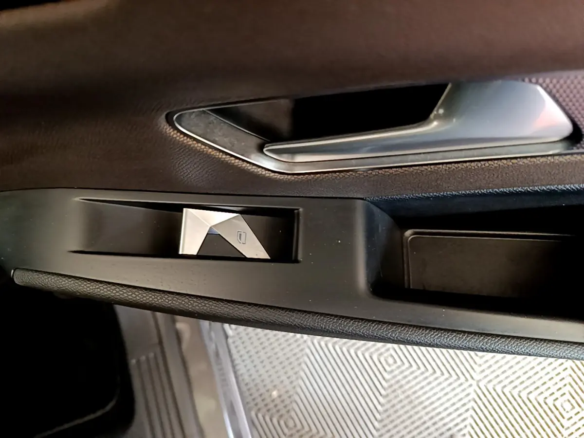 Gros plan sur la poignée intérieure et commande de lève-vitre côté gauche du DS7 Crossback gris foncé.