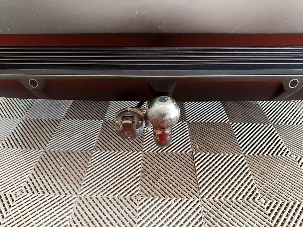 Gros plan sur l'attelage arrière d'un DS7 Crossback gris foncé, avec prise électrique intégrée sous le pare-chocs.