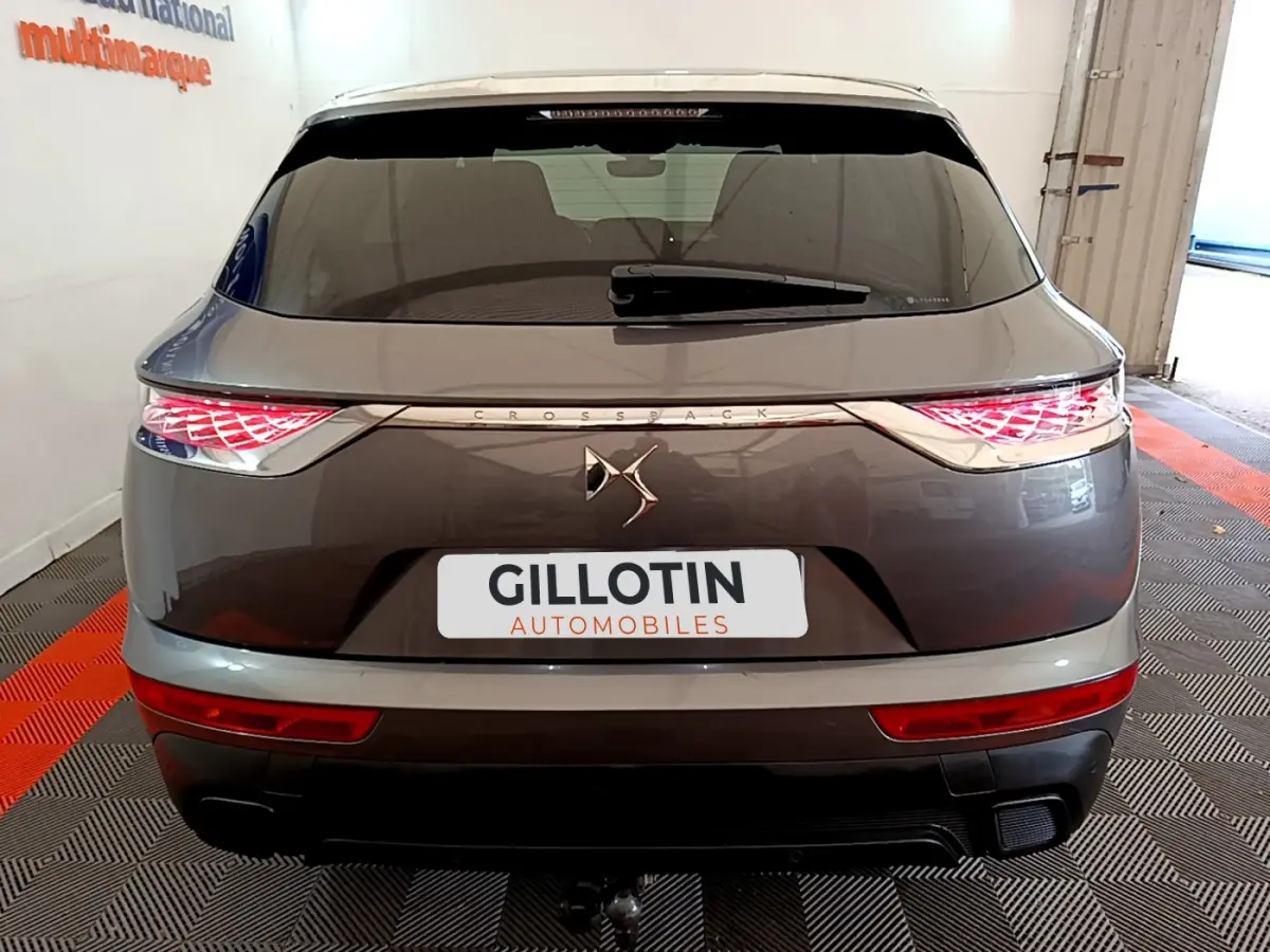 Vue arrière d’un DS7 Crossback gris foncé avec feux LED allumés et logo DS centré sur le hayon.