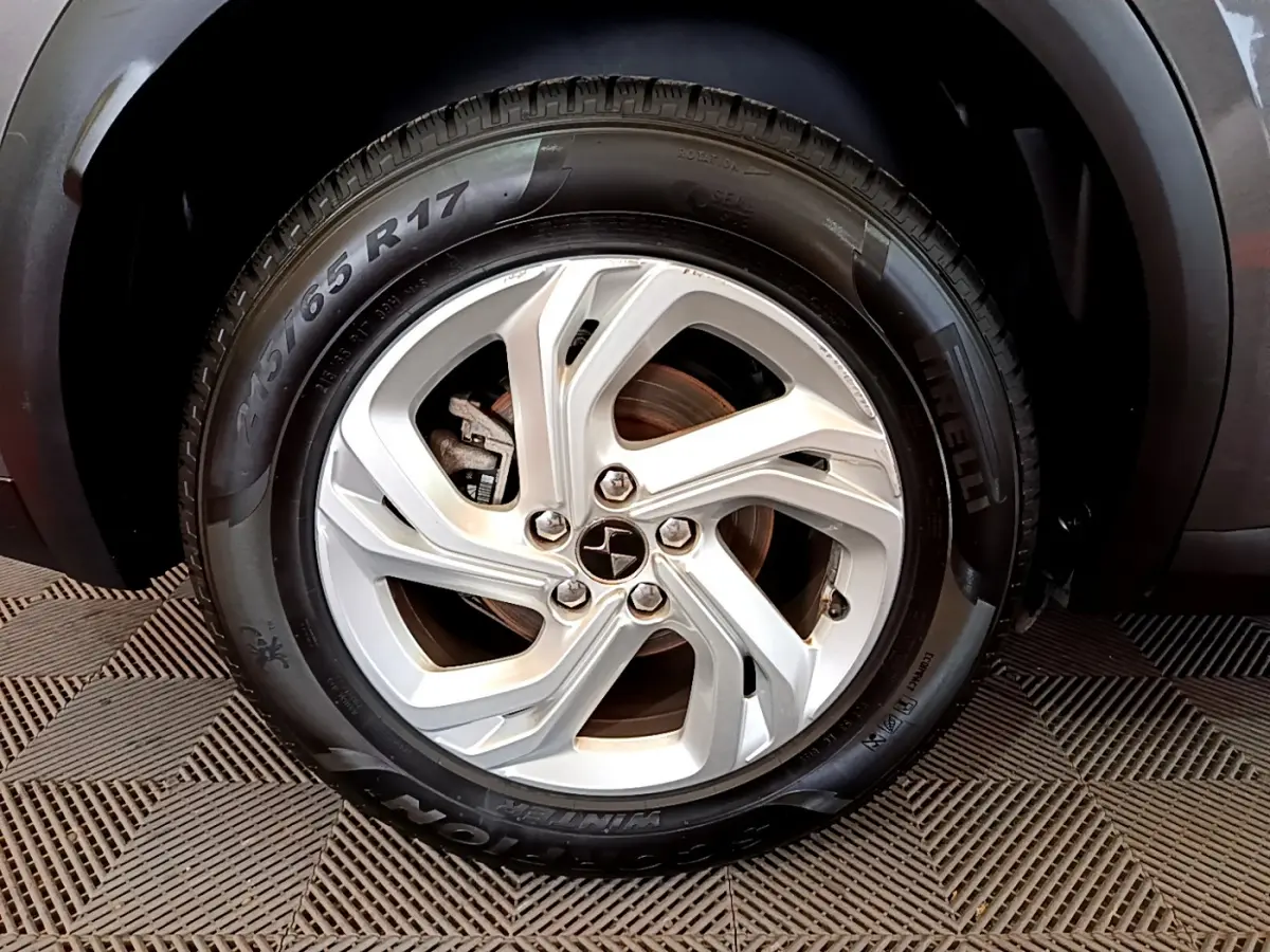 Gros plan sur la roue avant droite d’un DS7 Crossback gris foncé, mettant en valeur le pneu Pirelli et l’arche de roue.
