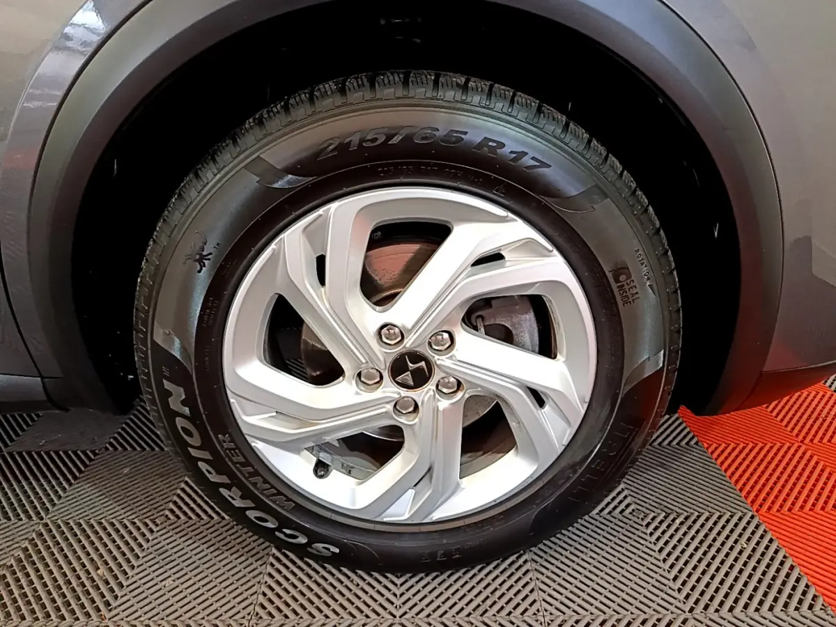 Gros plan sur la roue avant droite gris foncé du DS7 Crossback avec jante argentée et pneu hiver Pirelli.