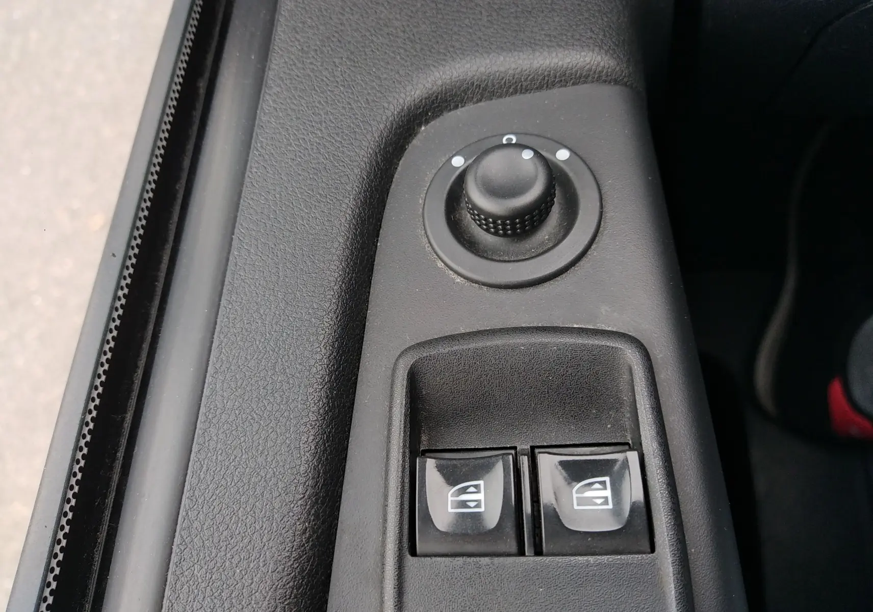 Gros plan sur les commandes de réglage des rétroviseurs et des vitres électriques côté conducteur d'un Renault Trafic Microbus blanc.