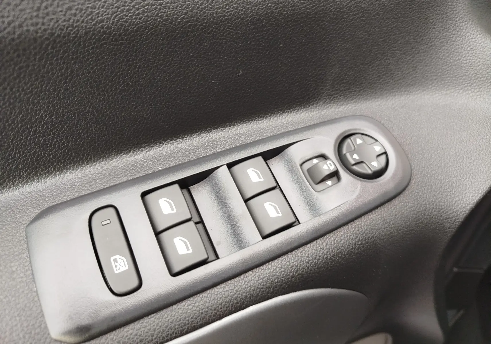 Gros plan sur les commandes de lève-vitres et rétroviseurs côté gauche, intérieur noir du Citroën Berlingo Kaolin White 2025.