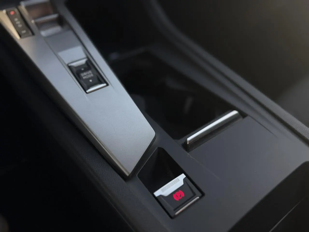 Gros plan sur la console centrale de la Peugeot 308 1.5 BlueHDI 130 Allure, avec frein de parking électrique activé.