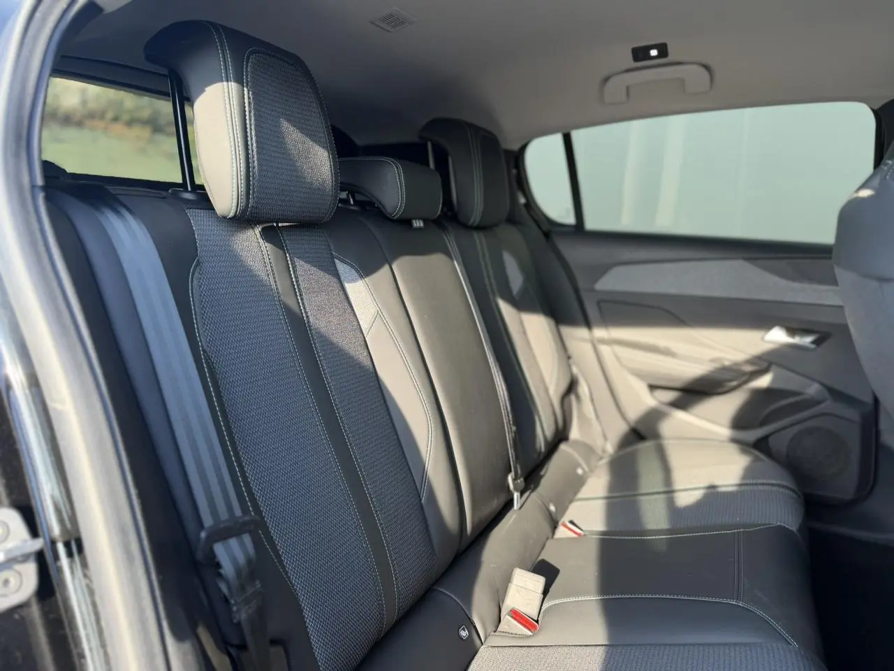 Vue latérale gauche des sièges arrière en tissu et cuir noir de la Peugeot 308 2025, avec ceinture de sécurité visible.