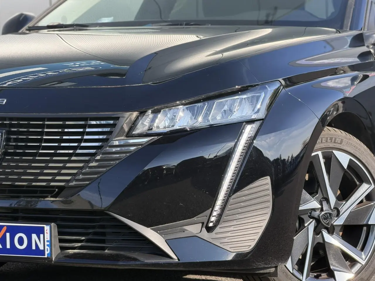 Gros plan 3/4 avant droit d’une Peugeot 308 noire Perla avec feux LED et jante alliage 17 pouces.
