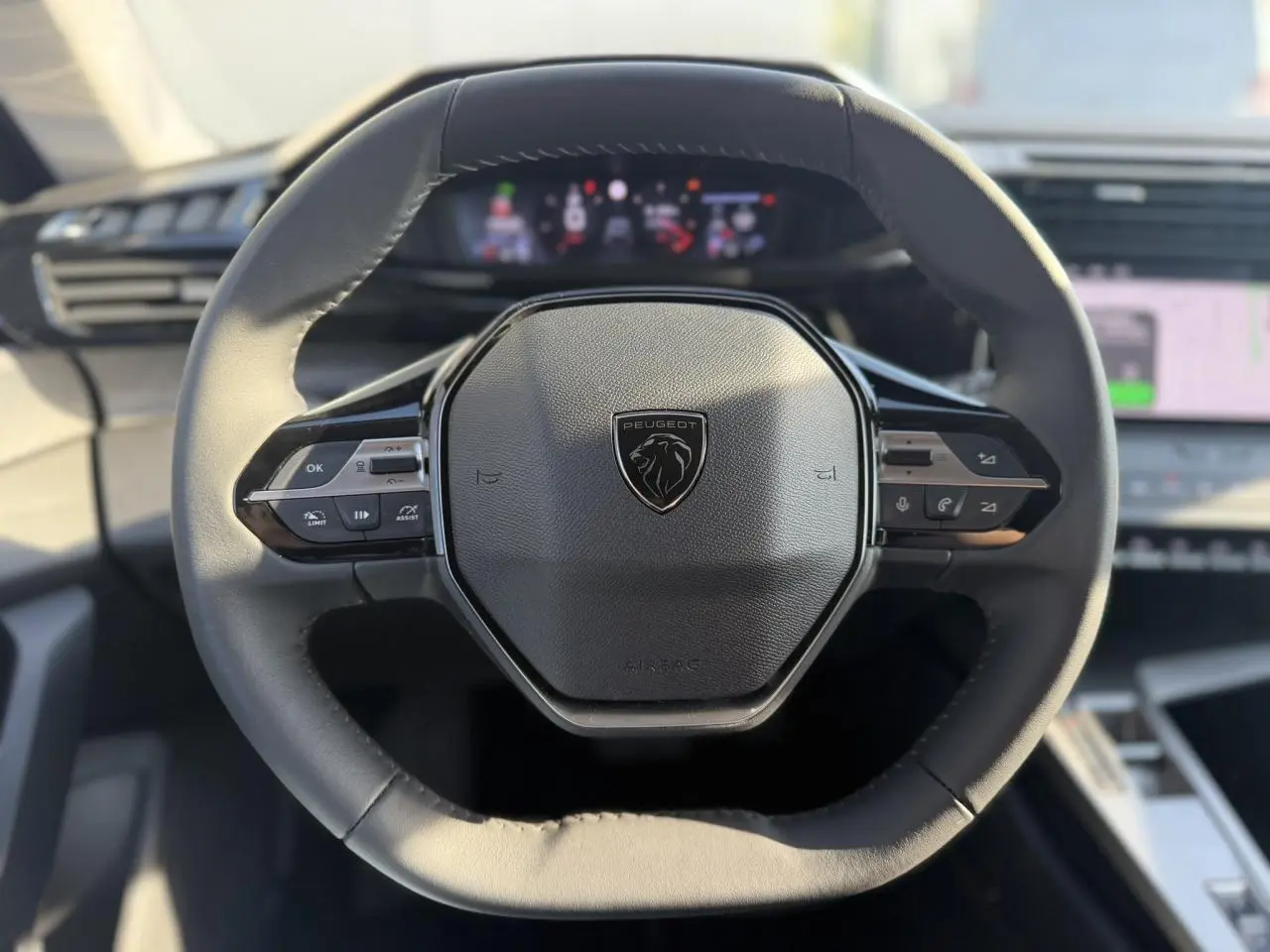 Vue rapprochée du volant cuir noir du Peugeot 308 2025 avec commandes intégrées et tableau de bord numérique flou.