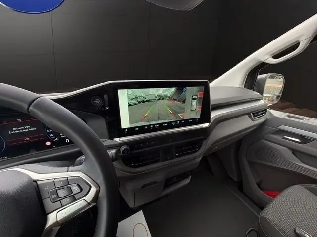 Vue intérieure côté conducteur du Volkswagen Transporter gris foncé 2026, avec écran tactile central affichant la caméra de recul.