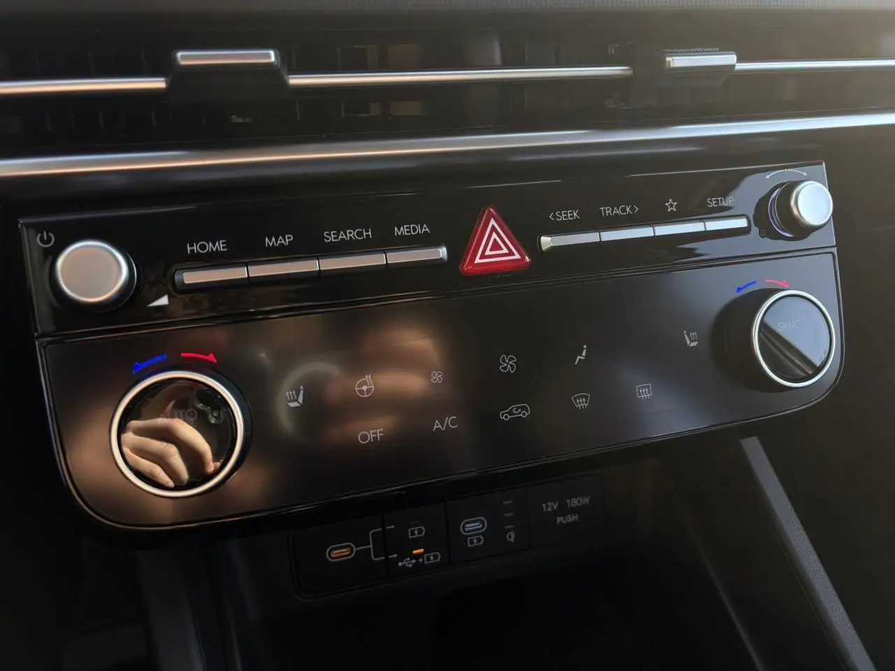 Tableau de bord du Hyundai Tucson 2025 en gros plan, avec commandes climatisation et multimédia noires brillantes.