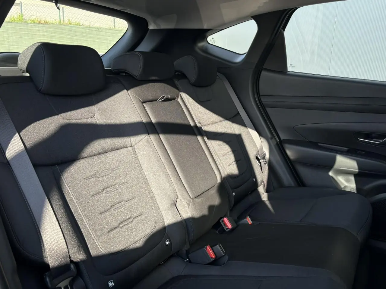 Vue côté droit de la banquette arrière noire du Hyundai Tucson 2025, avec appuie-têtes et ceinture de sécurité visibles.