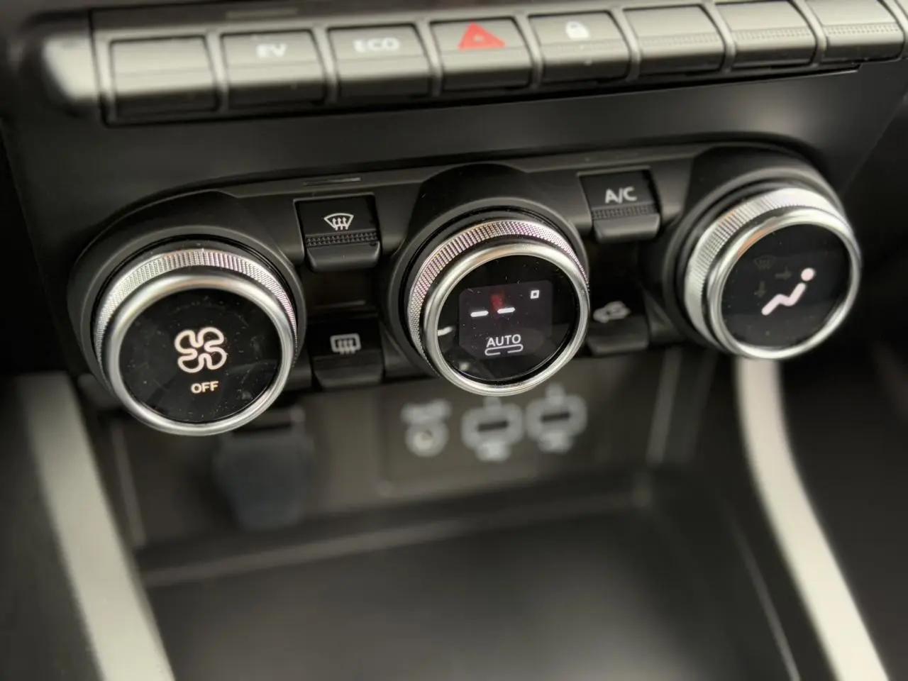 Gros plan sur les commandes de climatisation automatique du Renault Arkana E-Tech noir métal, avec réglages rotatifs et affichage digital.