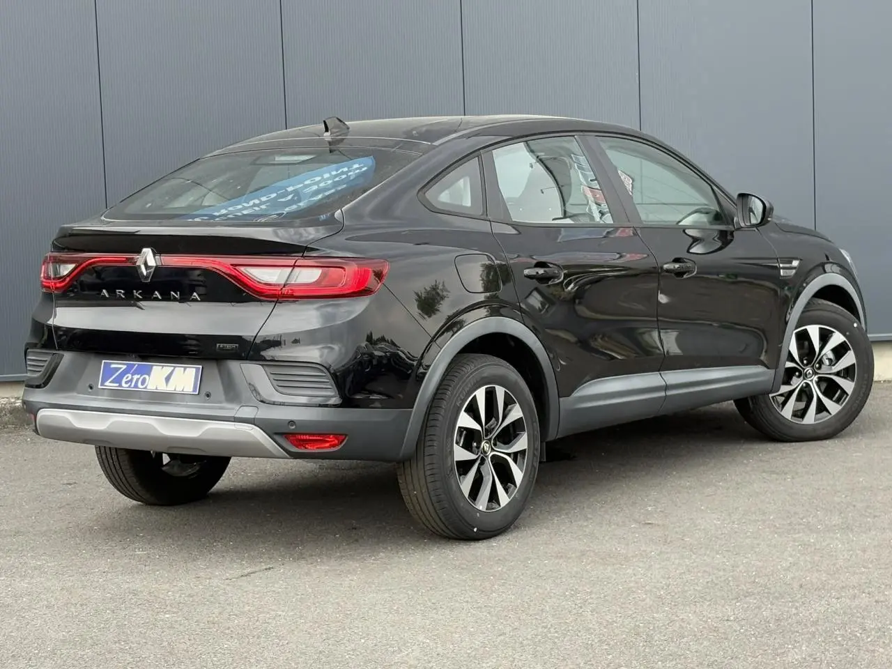 Vue 3/4 arrière droite d'un Renault Arkana noir métal 2024 avec jantes alliage et feux arrière LED distinctifs.