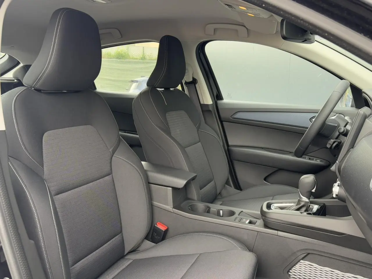 Vue intérieure côté droit du Renault Arkana E-Tech Full Hybrid 145 Evolution 2024, sièges tissu noir avec accoudoir central.
