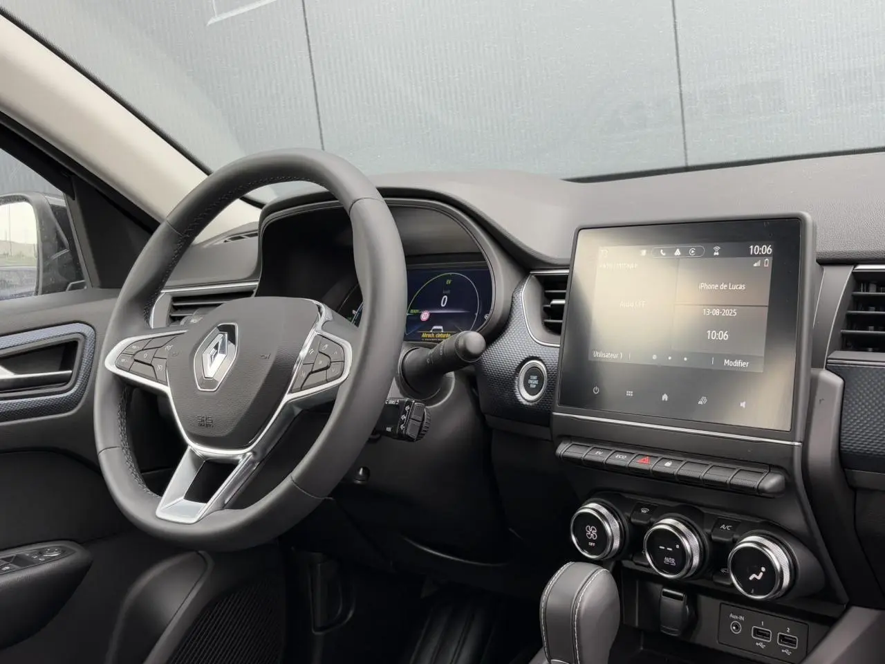 Intérieur du Renault Arkana E-Tech 2024 vu côté conducteur, tableau de bord noir avec écran tactile central et volant multifonction.