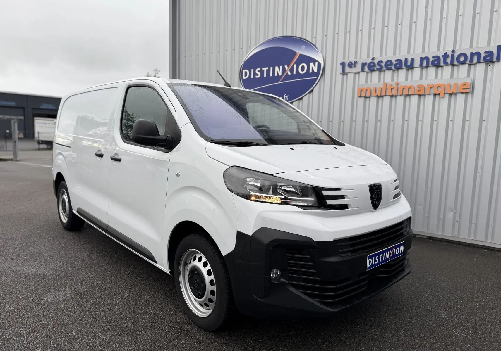 Vue 3/4 avant d'un utilitaire Peugeot Expert FGN blanc 2024, avec calandre noire et phares LED sous abri.