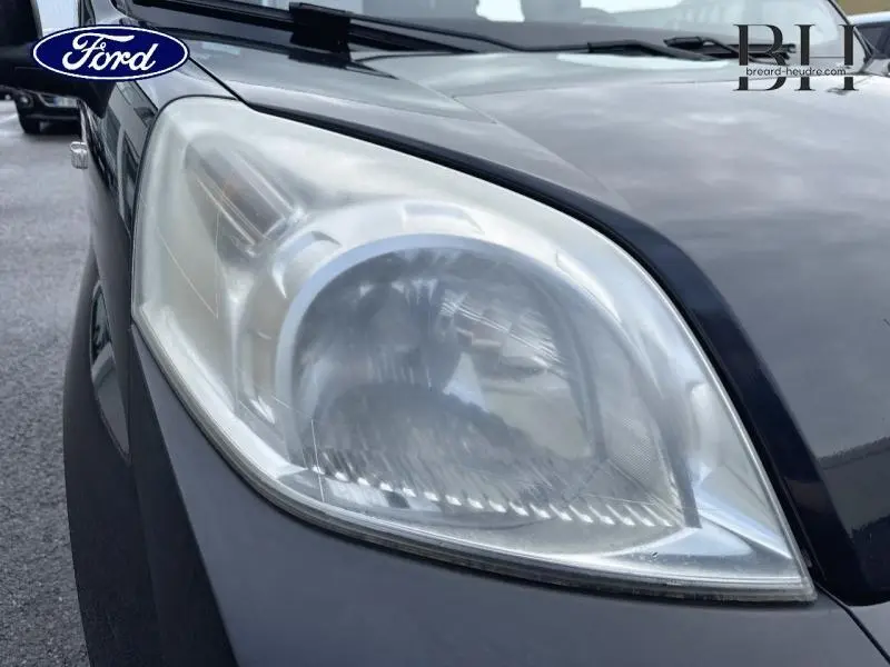 Gros plan sur le phare avant gauche d'un Citroën Nemo gris Graphito, montrant le capot et le pare-chocs.