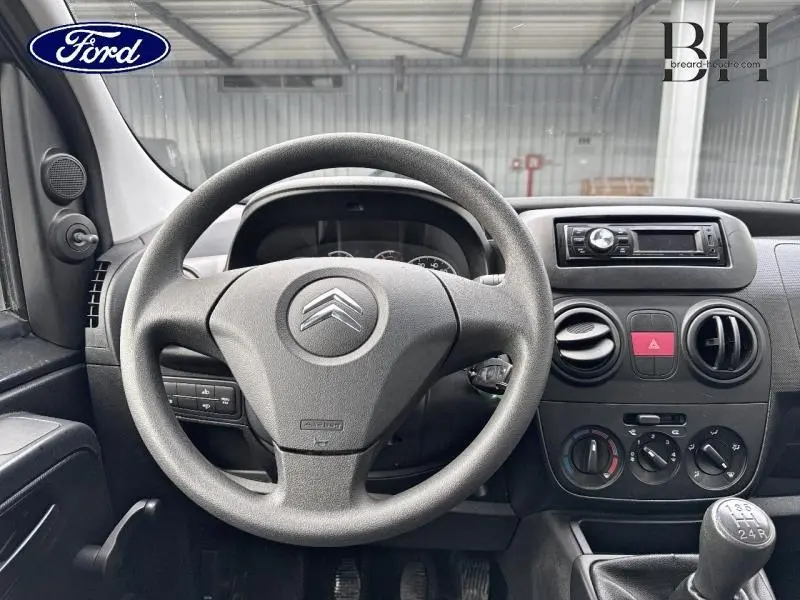 Vue intérieure du tableau de bord et volant noir du Citroën Nemo 1.4i Confort 2013 avec boîte manuelle.